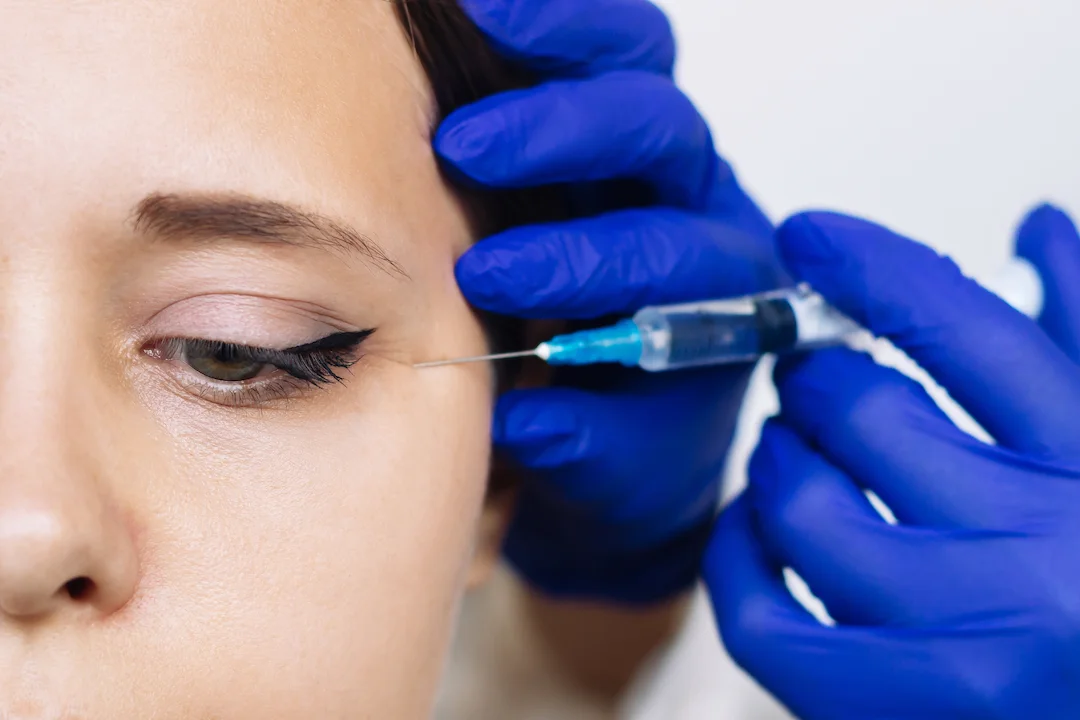 doctor hands blue gloves holding syringe needle injection facial wrinkles near eyes 1